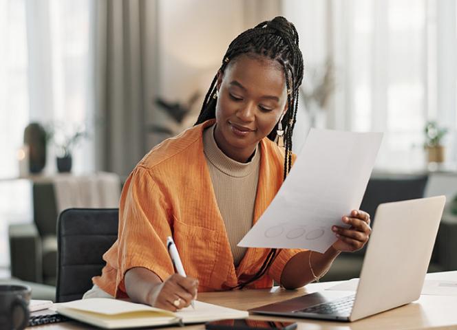 jeune femme étudiante qui travaille sur son ordinateur et prend des notes