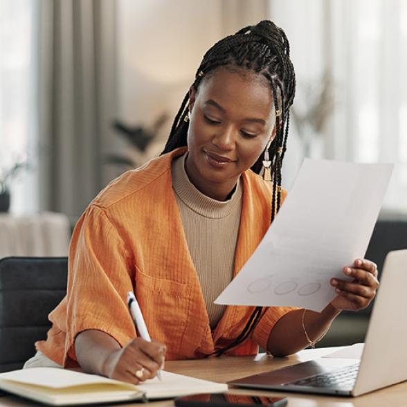 jeune femme étudiante qui travaille sur son ordinateur et prend des notes