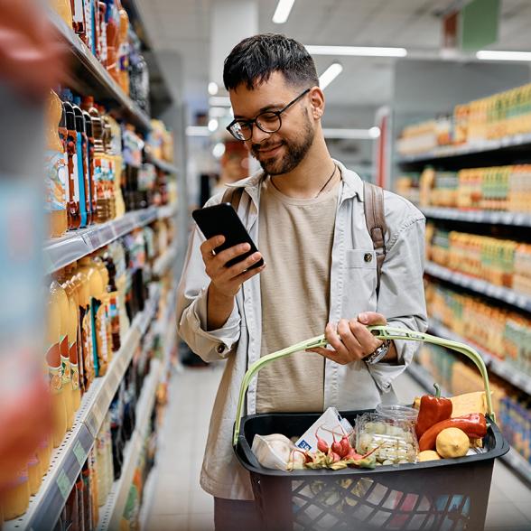 jeune homme qui regarde son téléphone en faisant ses courses